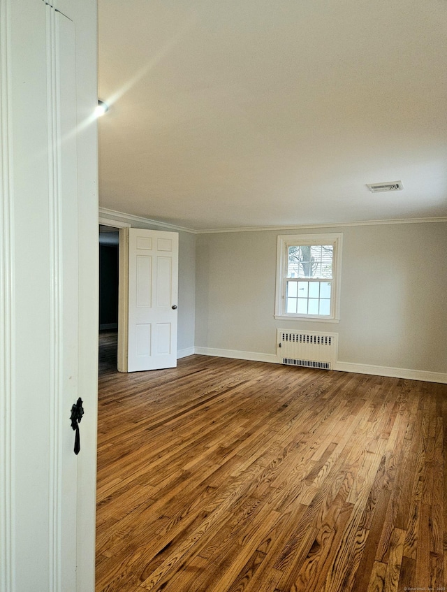 unfurnished room featuring radiator, hardwood / wood-style flooring, and ornamental molding