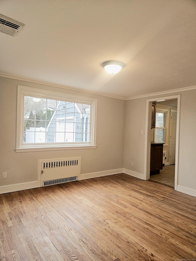 spare room with crown molding, radiator, and light hardwood / wood-style floors