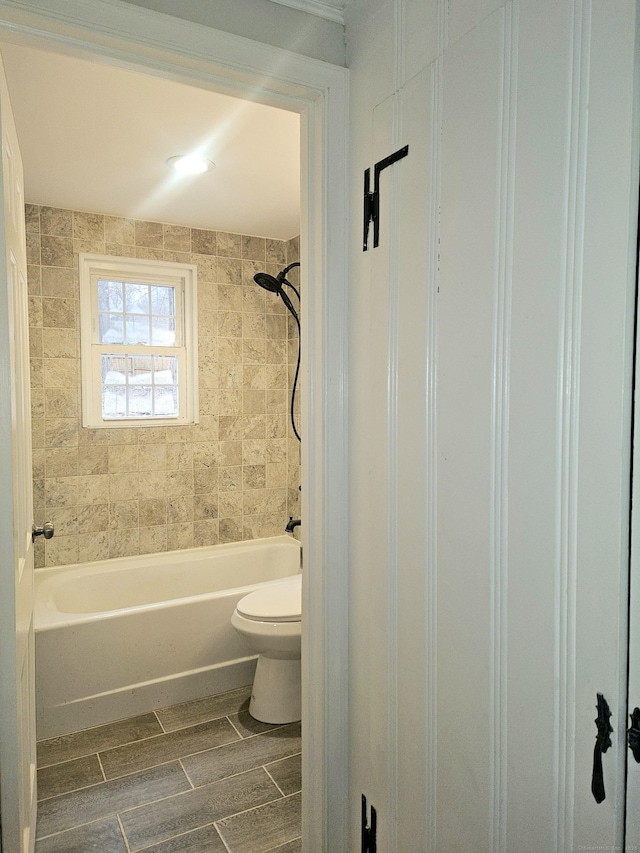 bathroom with toilet and tiled shower / bath combo