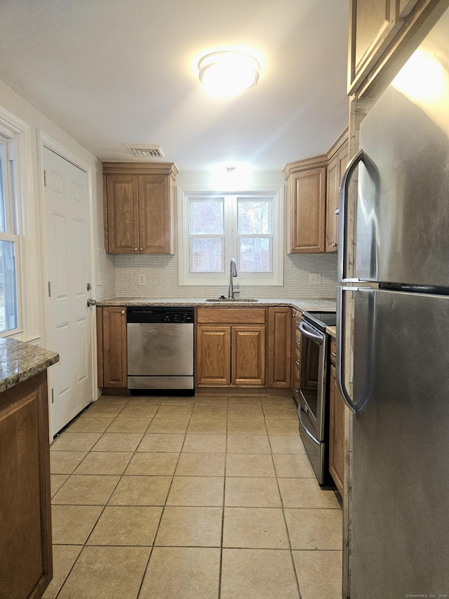 kitchen featuring stainless steel appliances, light tile patterned flooring, light stone countertops, and sink