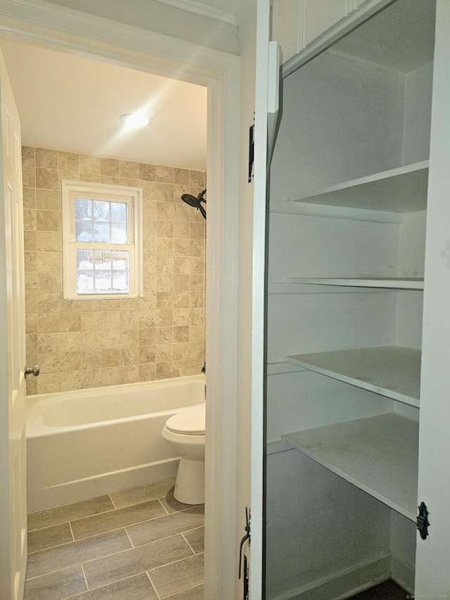 bathroom featuring tiled shower / bath and toilet