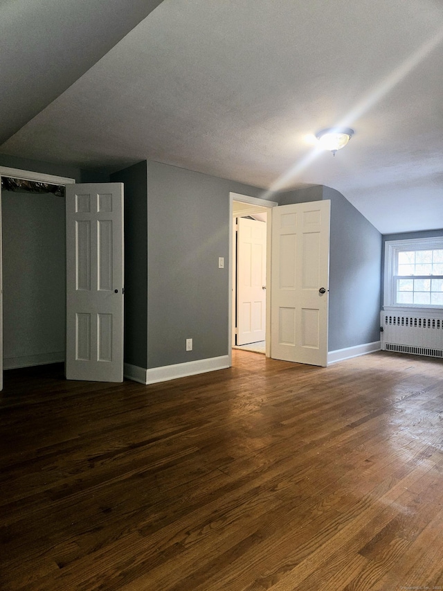 additional living space with dark hardwood / wood-style flooring, radiator heating unit, and lofted ceiling