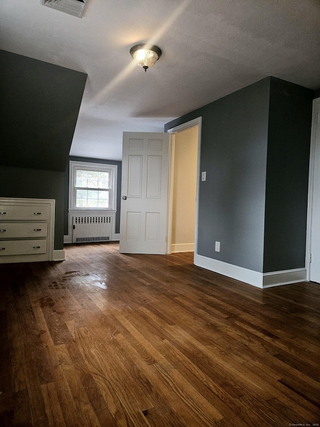 bonus room featuring radiator heating unit, dark hardwood / wood-style floors, and a textured ceiling