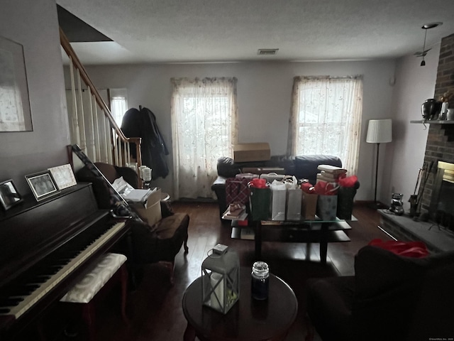 living room with dark wood-type flooring, a textured ceiling, and a fireplace