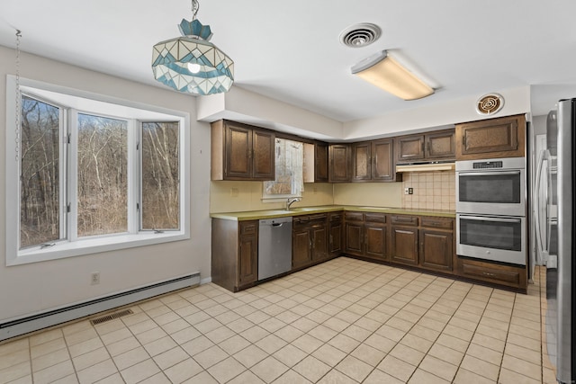 kitchen with appliances with stainless steel finishes, decorative light fixtures, decorative backsplash, a baseboard heating unit, and dark brown cabinets