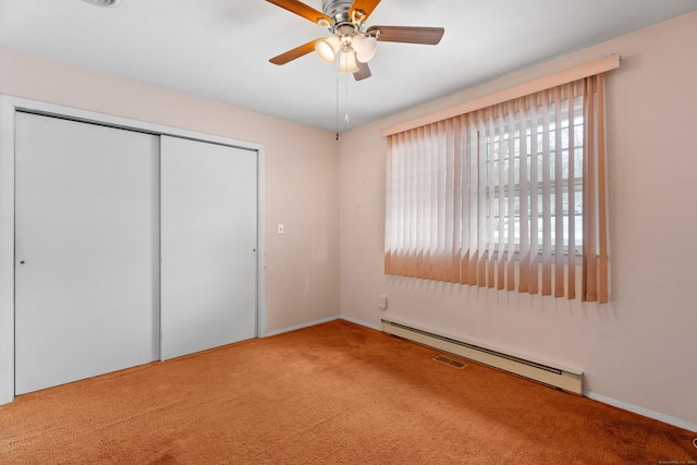 unfurnished bedroom with ceiling fan, carpet, baseboard heating, and a closet