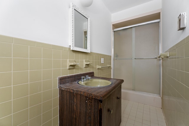 bathroom featuring tile patterned flooring, vanity, tile walls, and a shower with shower door