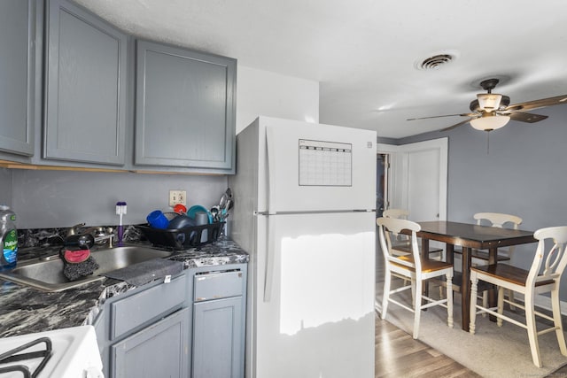 kitchen featuring sink, white refrigerator, ceiling fan, hardwood / wood-style floors, and stove