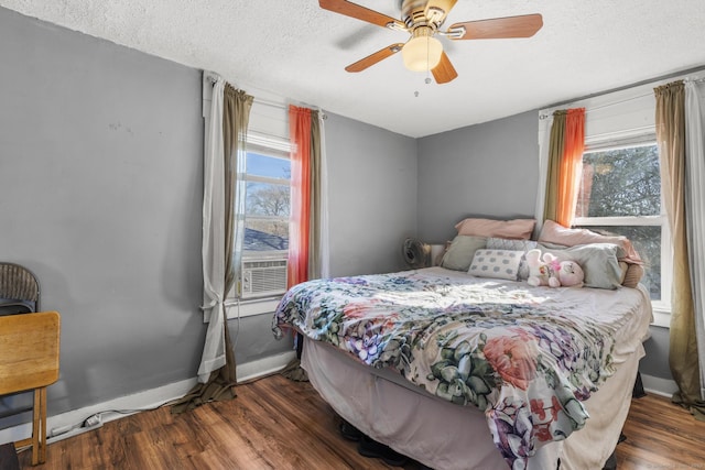 bedroom with multiple windows, dark hardwood / wood-style floors, and a textured ceiling