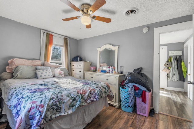 bedroom with ceiling fan, dark wood-type flooring, and a textured ceiling