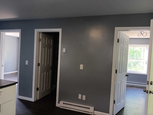 corridor with a baseboard radiator and dark hardwood / wood-style floors