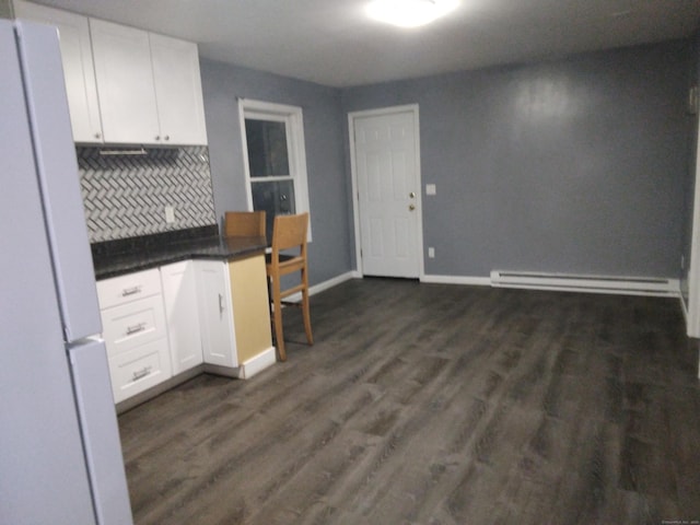 kitchen with white refrigerator, a baseboard radiator, dark hardwood / wood-style floors, decorative backsplash, and white cabinets