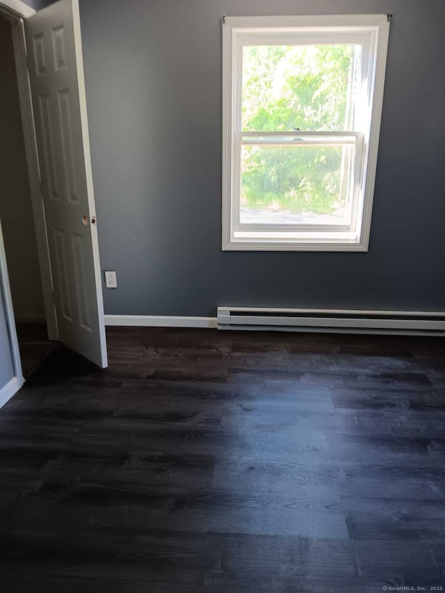 empty room featuring baseboard heating and dark wood-type flooring