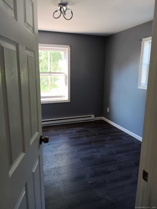 empty room featuring dark hardwood / wood-style flooring and a baseboard heating unit