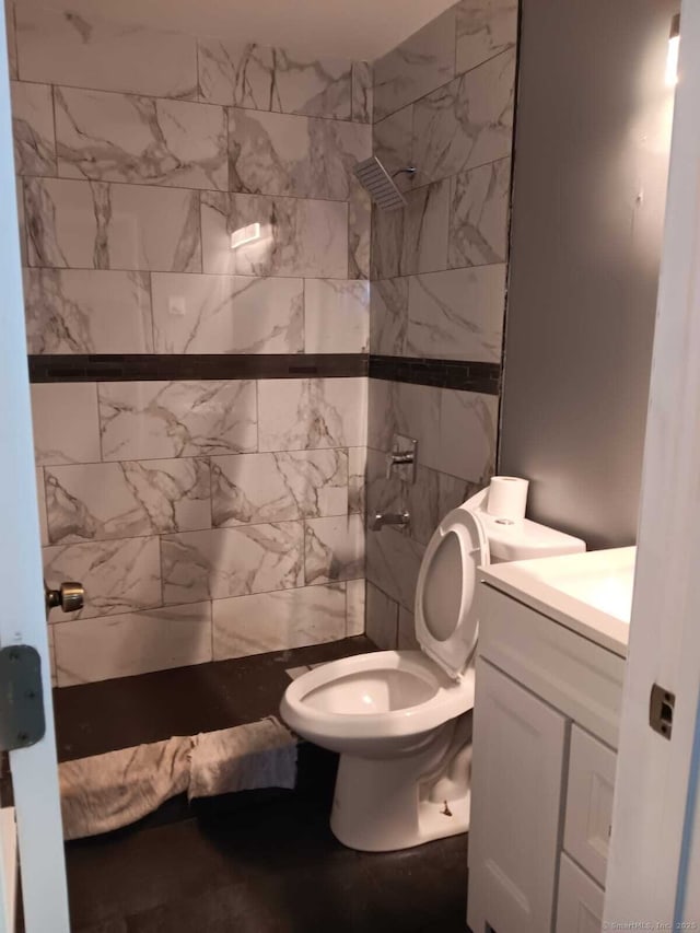 bathroom with vanity, a tile shower, and toilet