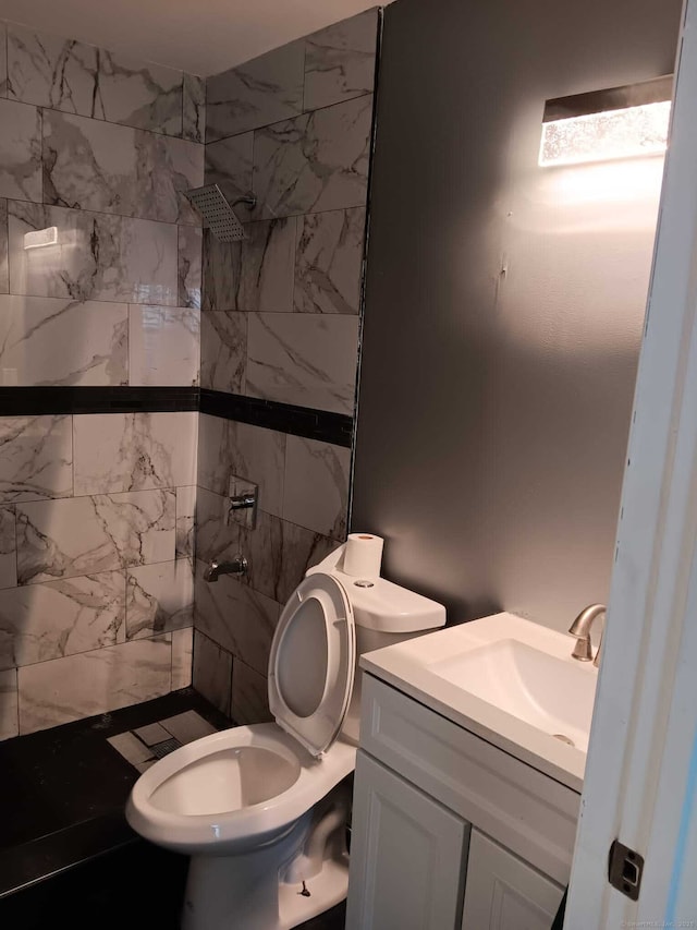 bathroom featuring vanity, a tile shower, and toilet