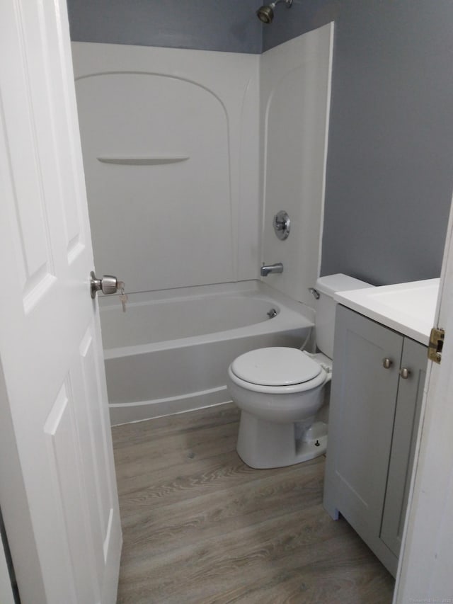 full bathroom with  shower combination, toilet, hardwood / wood-style floors, and vanity