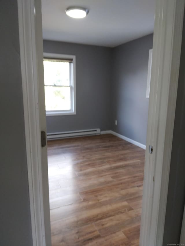 spare room featuring baseboard heating and hardwood / wood-style floors