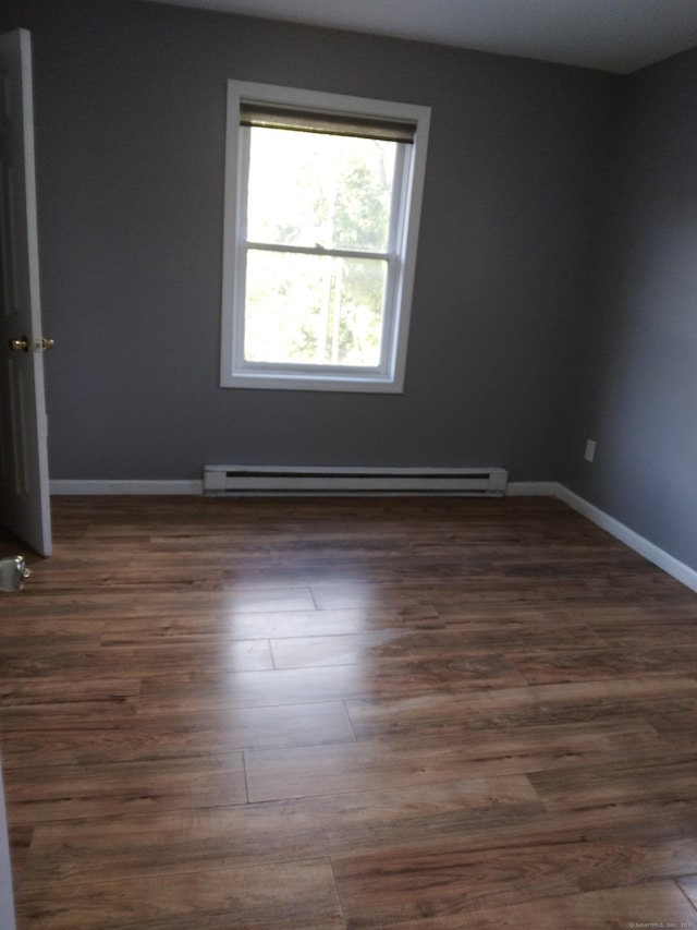 unfurnished room with a baseboard radiator and dark hardwood / wood-style floors