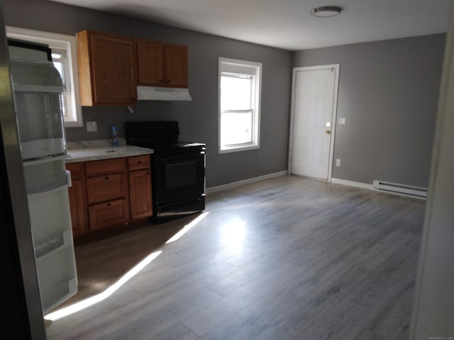 kitchen with black electric range oven, hardwood / wood-style flooring, and baseboard heating