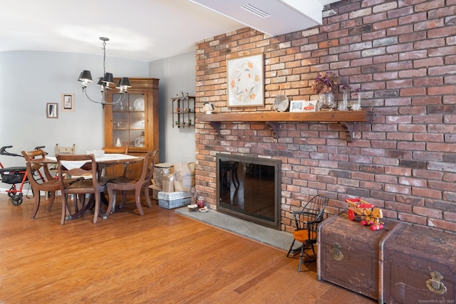 dining room featuring an inviting chandelier, hardwood / wood-style flooring, and a fireplace