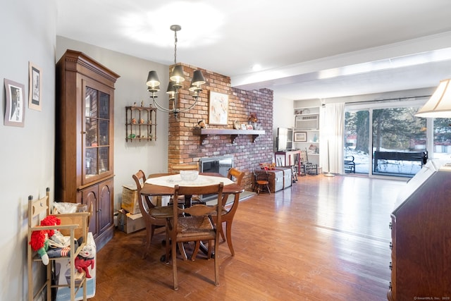 dining space featuring an inviting chandelier, hardwood / wood-style floors, a wall mounted air conditioner, and a brick fireplace