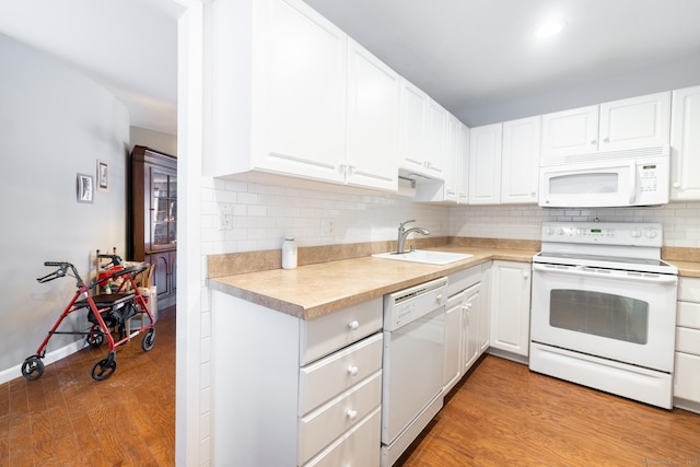 kitchen featuring sink, white appliances, light hardwood / wood-style flooring, white cabinetry, and backsplash