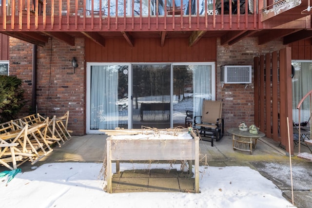 snow covered patio with an AC wall unit