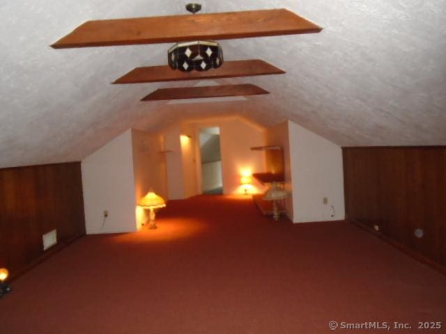 additional living space with lofted ceiling with beams, carpet floors, and a textured ceiling