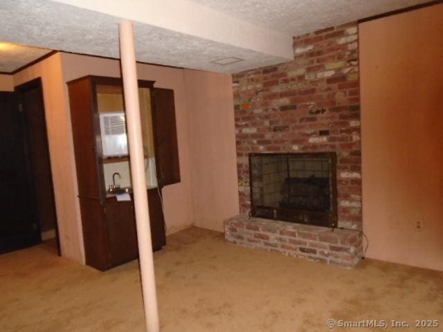 basement featuring a brick fireplace, light colored carpet, and a textured ceiling