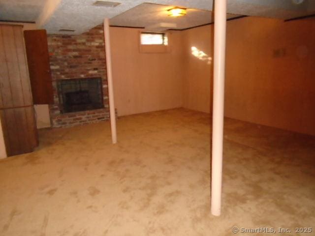 basement featuring a brick fireplace and carpet flooring