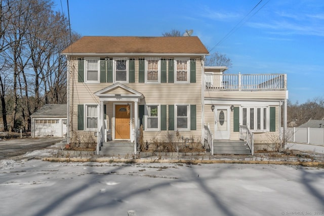 colonial home featuring a garage, a balcony, and an outdoor structure