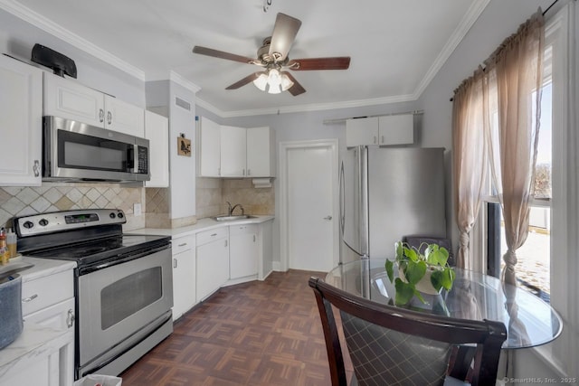 kitchen with sink, white cabinetry, crown molding, appliances with stainless steel finishes, and dark parquet floors