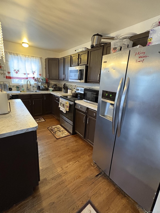 kitchen with dark brown cabinetry, sink, dark hardwood / wood-style flooring, and stainless steel appliances