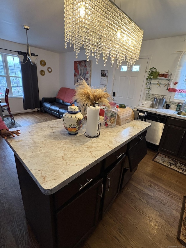 kitchen featuring a center island, stainless steel dishwasher, dark hardwood / wood-style floors, a notable chandelier, and pendant lighting