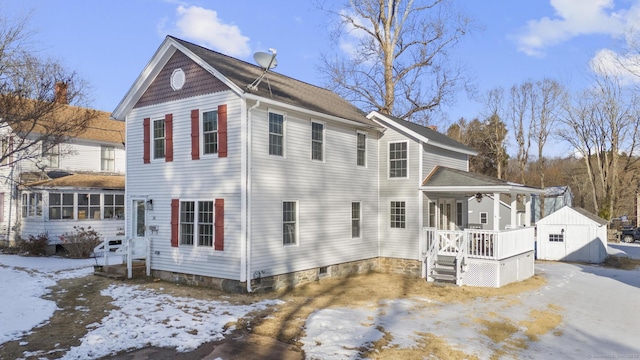 view of snow covered exterior featuring a storage unit and a porch