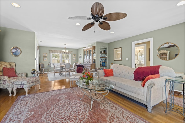 living room featuring wood-type flooring and ceiling fan with notable chandelier