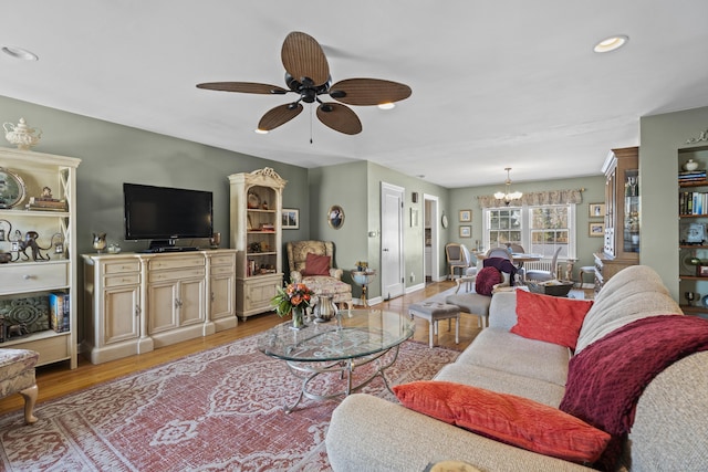 living room with ceiling fan with notable chandelier and light hardwood / wood-style floors