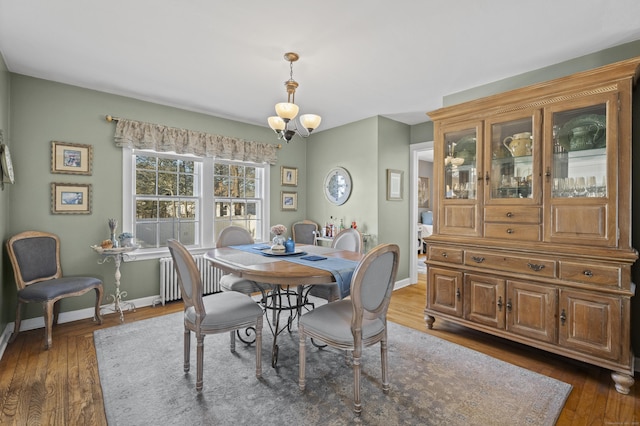 dining area with dark wood-type flooring, radiator, and an inviting chandelier