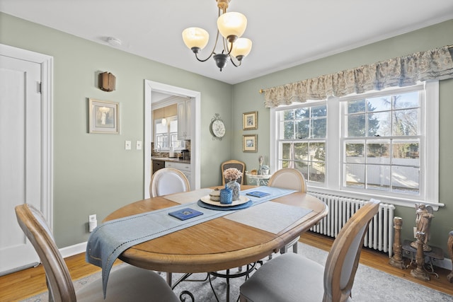 dining area with radiator, a notable chandelier, and light hardwood / wood-style floors