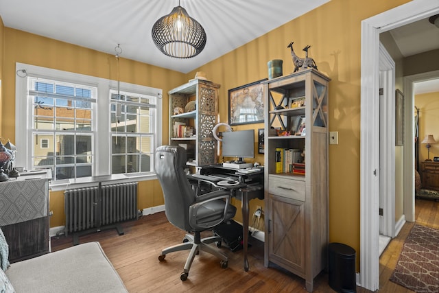 home office with radiator heating unit and hardwood / wood-style floors