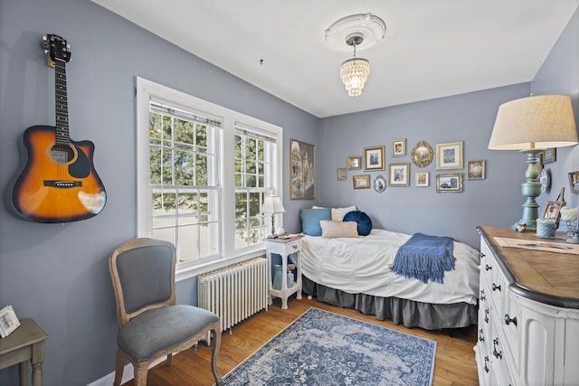 bedroom with radiator heating unit and light hardwood / wood-style floors