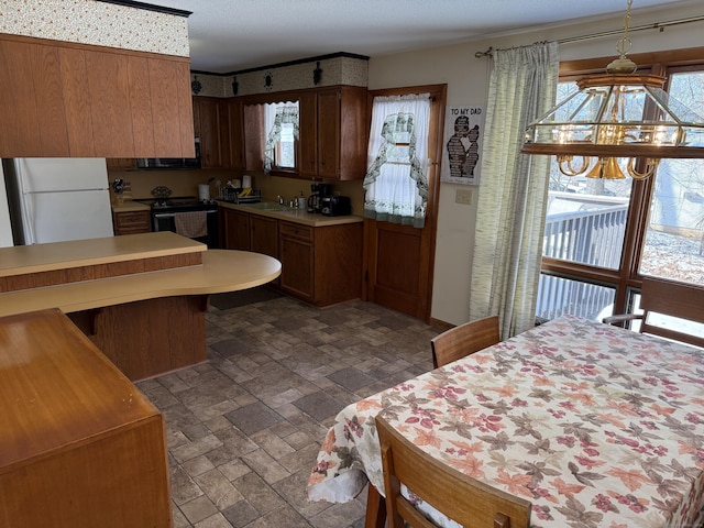 kitchen with a notable chandelier, sink, white fridge, and electric range