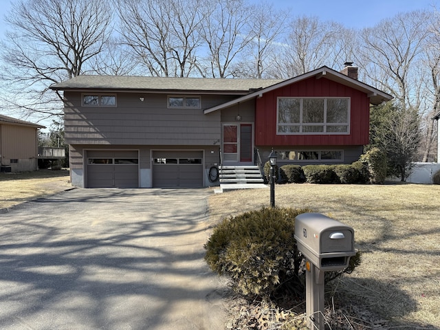 bi-level home with an attached garage, a chimney, and driveway