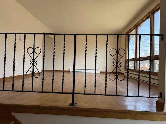 interior details with a baseboard radiator, baseboard heating, wood finished floors, and a gate