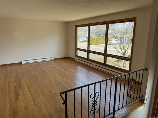 spare room with wood finished floors, baseboards, and a baseboard radiator