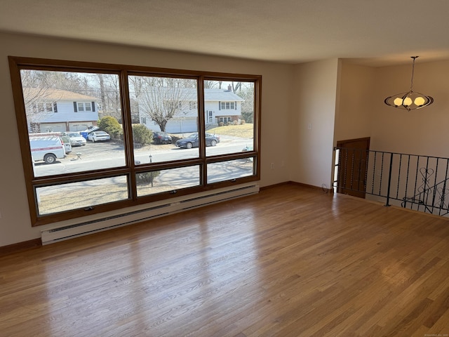 spare room with a baseboard heating unit, baseboards, and wood finished floors