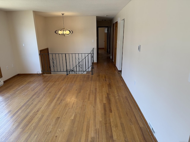 empty room featuring wood finished floors, visible vents, and baseboards