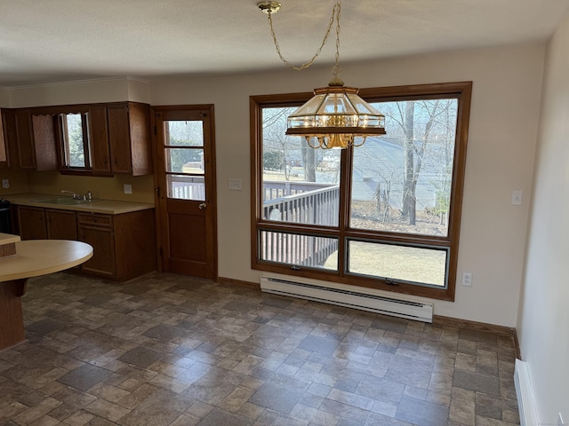 unfurnished dining area with baseboard heating, stone finish floor, baseboards, and a sink