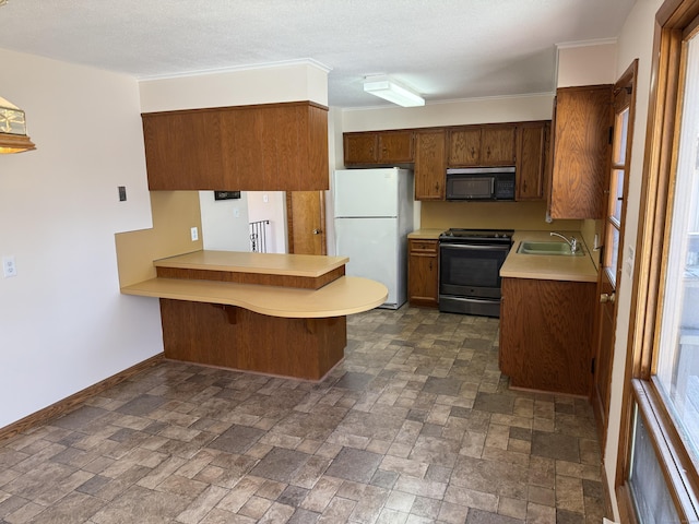 kitchen with black appliances, a sink, a peninsula, light countertops, and baseboards